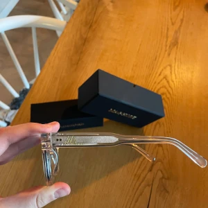 Transparenta solglasögon från Maggiore - Snygga solglasögon med transparent båge och mörka linser från Maggiore. Den rektangulära formen ger en modern look och de är perfekta för soliga dagar. Kommer med originalförpackning.