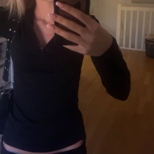 Svart långärmad tröja med dragkedja - Snygg svart långärmad tröja med dragkedja framtill. Perfekt för en stilren look och enkel att matcha med olika outfits.