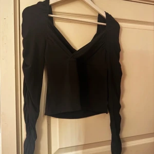 Svart långärmad topp från BikBok - Snygg svart långärmad topp från BikBok med rynkade detaljer på ärmarna och en v-ringad design, använd 1 gång.