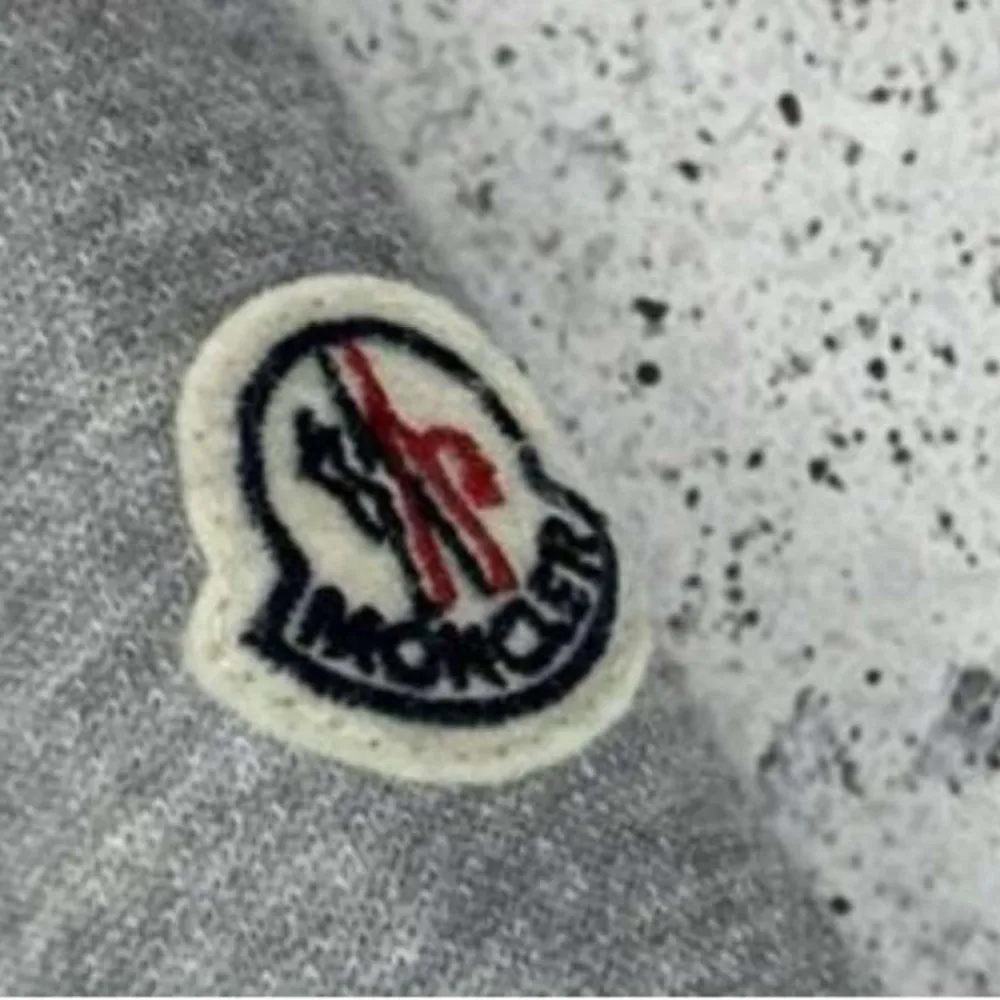Säljer en stilren grå pufferjacka från Moncler med dragkedja och ribbad krage. Jackan har långa ärmar i en kontrasterande grå nyans och Moncler-logga på ärmen. Perfekt för kyligare dagar.. Takit.