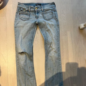 Ljusblå jeansbyxor från Only - HAR INGA BILDER Säljer ett par ljusblå jeansbyxor från Only. De har en klassisk femficksdesign och en slitning på ena benet för en cool look. Byxorna har en låg midja och en straight passform som ger en avslappnad stil. Midja: 39. W29 L34 INNERBEN:80