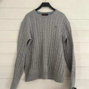 Grå kabelstickad tröja från Morris - Säljer en stilren grå kabelstickad tröja från Morris i 100% pima bomull. Tröjan har ett diskret broderat emblem på bröstet och ribbade muddar vid ärmslut och nederkant. Mvh GrischBolaget👟