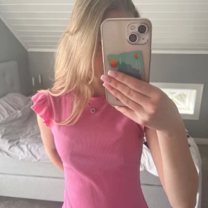 Rosa ribbad topp med volangärmar - Säljer en söt rosa ribbad topp med volangdetaljer vid ärmarna. Perfekt för en somrig look.💕