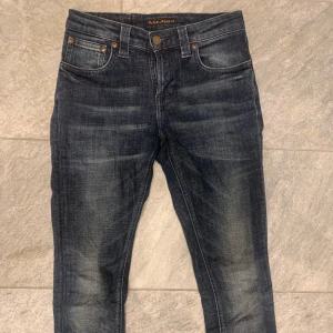 Mörkblå jeans från Nudie Jeans - Snygga mörkblå jeans från Nudie Jeans med klassisk femficksdesign och orange sömmar. Jeansen har en lätt tvättad look och en bekväm passform. Perfekta för en avslappnad stil. De är i storlek 26/32 men sitter mer som 27 i midjan!👍