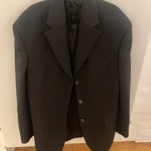 Svart kavaj från Acne Studios - Snygg svart kavaj från Acne Studios. Kavajen har en klassisk design med knappar framtill och fickor på sidorna. Den är perfekt för både vardag och fest. Den är i fint skick. Storlek 34. Rökfritt hem. Skickar paket som spårbart.