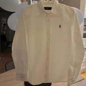 Vit Ralph Lauren skjorta - Säljer en vit skjorta från Ralph Lauren storlek 170 M. Skicket är 10/10 och är använd 1 gång i Grekland. Jag är 170 cm och den passar mig perfekt.