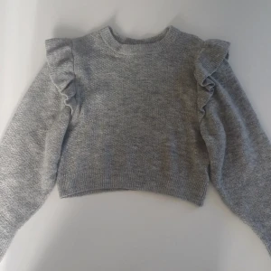 Grå tröja💗 - Säljer en snygg grå croppad tröja från hm med volangdetaljer på axlarna. Tröjan har långa ärmar och är perfekt för en trendig look. Har en jätte fin passform💕