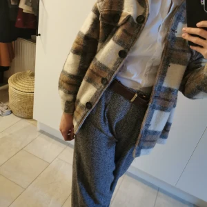 Rutig jacka i bruna och vita toner - Säljer en snygg rutig jacka från Zara i bruna och vita toner. Jackan har stora knappar och en klassisk krage. Perfekt för höst och vår med sin mysiga och stilrena design. Längd: 67cm. Bredd:60cm. Armlängd: 53cm