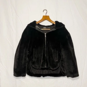 Svart pälsjacka från Zara - Säljer en snygg svart vegan pälsjacka från Zara med dragkedja och huva. Jackan har en mjuk och lyxig känslal. Den har en stilren design som passar till många olika outfits. Den är otroligt mjuk och härlig ⭐️ Storleken är XS men skulle säga att den är stor i storleken ☺️