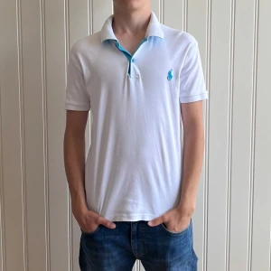 Polo ralph lauren piké - Säljer en snygg vit pikétröja från Polo Ralph Lauren i storlek S. Tröjan har en klassisk krage med knappar och en stilren blå logga på bröstet. Perfekt för en avslappnad men ändå stilren look. Passar bra till både jeans och shorts!