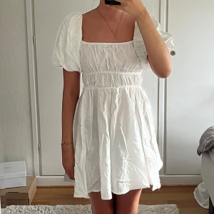 Vit studentklänning från Chiquelle - Supersöt vit kort klänning från Chiquelle i storlek XS. Klänningen har puffiga korta ärmar och fyrkantig urringning. Perfekt till student/skolavslutning/konfirmation. 