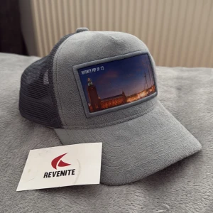  Grå Revenite keps med Stockholms motiv - Köptes sommaren 2023, har bara kommit till användning fåtal gånger och inga defekter! Limited edition keps, säljs inte längre!!