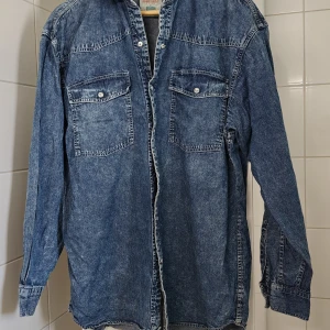 Blå jeansskjorta vintage 1980 tal strl L - Snygg blå vintage jeansskjorta från Western Shirt by Best in Town i storlek L. Klassisk westernstil med två bröstfickor med knappar, markerad söm över axlarna och långa ärmar. 