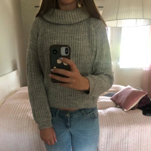 Grå stickad polotröja - Mysig grå stickad polotröja med hög krage som man kan vika ner och ribbat mönster. Tröjan har lång ärm som passar perfekt till jeans. Perfekt för kyliga dagar när du vill vara både bekväm och snygg. Super skön och gosig! Perfekt till hösten! Använd typ 1 gång!