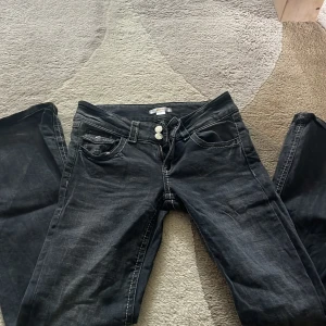 Gråa jeans från Gina Young - Snygga gråa jeans från Gina Young med kontrastsömmar och dubbla knappar i midjan. Klassisk femficksmodell med cool detalj på myntfickan. Jeansen har rak passform och är tillverkade i slitstarkt denimtyg. Jeansen är lite slitna nere vid benet men inget man tänker på. 