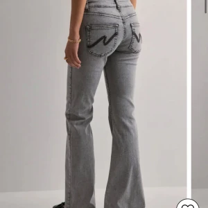 Grå bootcut jeans med låg midja - Original pris 700kr skriv för mer bilder Snygga grå jeans med bootcut passform och låg midja. Jeansen har markerade svarta sömmar och coola bakfickor med broderad detalj. Perfekta för dig som gillar en retro vibe och vill sticka ut lite extra. Tillverkade i klassiskt jeanstyg.