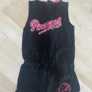 Svart Pineapple ärmlös topp med paljetter - Svart ärmlös topp från Pineapple med färgglatt paljettbroderi framtill och rosa dragkedja i ryggen. 