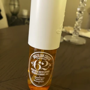 Brazilian Crush Cheirosa 62 Parfymmist - En söt och krämig parfymmist med doft av pistage och salt karamell. Flaskan är genomskinlig med orange vätska och har en vit spraykork. Perfekt för dig som älskar gourmanddofter och vill ha en tropisk vibe.