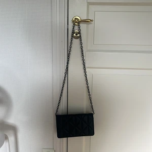 Svart quiltad axelväska med kedja - Snygg svart axelväska med quiltad design och lång kedjerem. Väskan har en rektangulär form och stilren look som passar till många outfits. Perfekt storlek för det viktigaste, använder inte längre och använd mindre än 5 ggr. Ser ut som ny, pris kan alltid diskuteras.❤️
