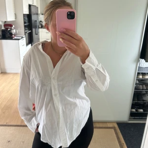 Vit oversized skjorta med knappar - Klassisk vit skjorta i oversized modell med långa ärmar och knäppning framtill. Skjortan har en avslappnad passform, krage och är tillverkad i ett tunt bomullstyg. Perfekt att styla med jeans eller leggings för en chill look.