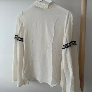 Vit blus med svart rand runt armen - Vit blus med svart pärl rand runt armen