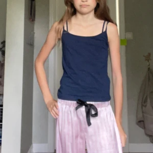 Mörkblå linnetopp från Gina Tricot - Enkel och stilren mörkblå linnetopp från Gina Tricot med smala axelband. Toppen är figurnära och passar perfekt till sommaren. Mjuk och skön bomullskänsla, lätt att matcha med både jeans och kjol.