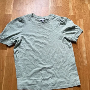 Ljusgrön topp från Vero Moda - Snygg ljusgrön topp från Vero Moda Aware med puffiga korta ärmar och rund halsringning. Tillverkad i mjuk bomull som känns skön mot huden. Enkel och stilren design som passar perfekt till jeans eller kjol.