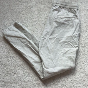 Beiga linnebyxor  - Snygga beiga linnebyxor från ONLY.  Byxorna har resår och snörning i midjan samt fickor på sidorna. Perfekta för en chill och avslappnad stil under varmare dagar. Mestadels legat i garderob men har används av min 14 åriga bror på midsommar samt skolavslutning