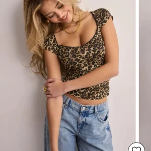 Leopardmönstrad topp med spetskant - Trendig leopardmönstrad topp från Gina Tricot med v-ringning och svart spetskant. Modellen är croppad med korta ärmar och figurnära passform. Toppens material är stretchigt och mjukt, perfekt för en trendig look.
