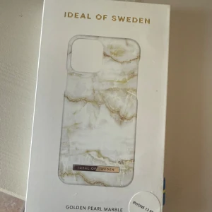 Marble iPhone 13 Pro skal Ideal of Sweden - Nytt & oöppnat! Snyggt mobilskal till iPhone 13 Pro från Ideal of Sweden i mönstret Golden Pearl Marble. Skalets design har en lyxig marmoreffekt i vitt och guldiga toner, med en elegant metallogo längst ner. Perfekt accessoar för att ge mobilen en stilren och trendig look.