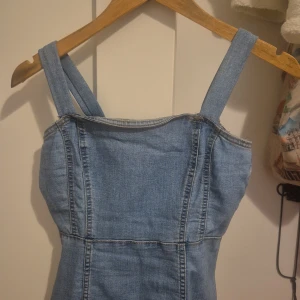 Jeansklänning från H&M Divided - Snygg ljusblå jeansklänning från H&M Divided med breda axelband och figurnära passform. Klänningen har markerade sömmar och är tillverkad i klassiskt denimtyg. Perfekt för en trendig och avslappnad look. Jag använde tyget från HM men gjorde nästan klänningen själv. Så ja axelbanden har jag också gjort själv. 