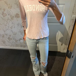 Ljusrosa långärmad tröja Bondelid - Ljusrosa långärmad tröja från Bondelid med vitt tryck framtill. Tröjan har en avslappnad passform, rund halsringning och trekvartsärm. Tillverkad i mjuk bomull, perfekt för vår och sommar. Enkel och stilren design som funkar till jeans eller kjol.