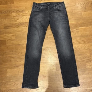 jack and jones svarta skinny jeans - Snygga svarta  jeans med skinny fit och klassisk femficksdesign. Jeansen har en mörk tvätt med lätt slitning och smal passform hela vägen ner. Perfekta för dig som gillar en modern och stilren look.