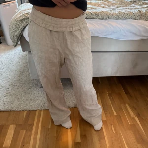 Beiga linnebyxor med snörning - Säljer ett par beiga linnebyxor med avslappnad passform och resår i midjan samt snörning framtill. Byxorna har raka ben och sidfickor🩵
