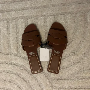 Skor - Snygga bruna sandaler från Zara med trendig fyrkantig tå och breda remmar i skinnimitation. Perfekta för varma dagar och ger en stilren touch till din outfit. Lätta att matcha och superbekväma att glida i.