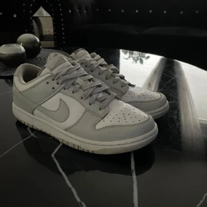 Nike Dunk Low - Vit och grå - Väldigt bra skick. Vårdade, helt vita, inga skavanker såsom färgen. Jätte bekväma och snygga skor, inga creases - använt med creaseskydd och de följer med. Fler bilder kan ges, jag ursäktar att det bilderna är lite olika - tog dem vid olika tillfällen då jag ville lägga till några bilder. Original förpackning ingår! Pris går att diskuteras vid snabbaffär. Kontakta mig gärna! Nypris 1499kr.