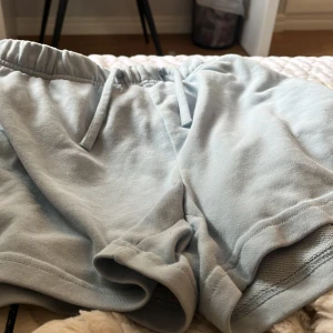 Ljusblå mjuka shorts med snörning - Superbekväma ljusblå shorts i mjukt material med elastisk midja och snörning. Perfekta för chill dagar eller träning. De har en avslappnad passform och är tillverkade i bomull med mesh-detaljer på insidan av benen.