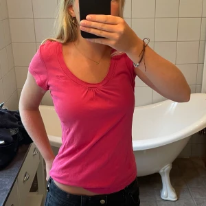 Rosa topp från edc med rund hals - Säljer en jättefin rosa topp från edc med rundad halsringning och lätt rynkdetalj framtill. T-shirten har korta ärmar och är gjord i mjuk bomull, perfekt för en chill och enkel stil.