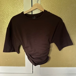 Brun croppad t-shirt med snörning - Trendig topp från gina tricot dom är figursydd i midjan. Aldrig använd, xxs men sitter mer som en xs 💘