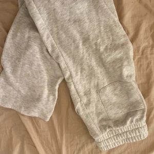 Grå mjukisbyxor - Ljusgrå mjukisbyxor från lager 157 i storlek S. Byxorna har resår och snörning i midjan samt resår. Mjukt material och en enkel ficka på benet. 