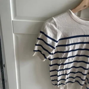 Randig t-shirt från Zara i bomull - Vit t-shirt från Zara med marinblå horisontella ränder. Klassisk rund halsringning och korta ärmar. Tillverkad i mjuk bomull, perfekt för en chill och stilren look.