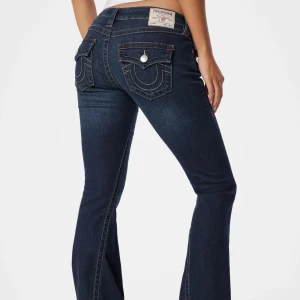 True Religion Joey Low Rise Flare Jeans - Mörkblå jeans från True Religion, modell Joey Low Rise Flare. Snygga kontrastsömmar, ikoniska ficklock med silverknappar och låg midja. Jeansen har bootcut/flare passform. Det är storlek 28  säljer pågrund av att de är för korta för mig som är ca 177 cm. Köptes på Plick innan men är i mycket bra skick