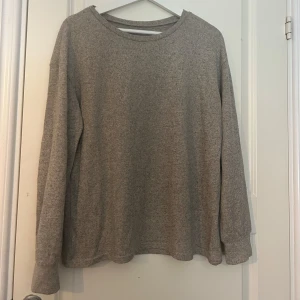  långärmad tröja i bomull - Enkel och stilren grå långärmad tröja med rund halsringning. Tröjan är i mjuk bomull och har en loose passform som gör den skön att bära. Perfekt för lager-på-lager och chill dagar.