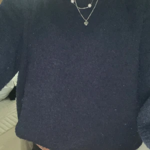 Mörkblå stickad tröja från Gina Tricot - Mysig mörkblå stickad tröja med enkel design och rund hals. Tröjan har lång ärm och en lite loose passform, perfekt för lager på lager under kyliga dagar. Passar dig som gillar en stilren och basic look.