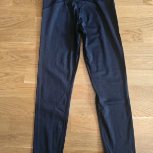 Svarta leggings med blå sömdetaljer - Svarta leggings med smal passform och blå sömdetaljer längs sidorna. Perfekta för träning eller en sportig look. Mjukt och stretchigt material som sitter bekvämt hela dagen.