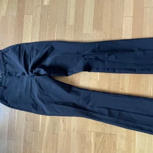 Svarta kostymbyxor från Bik Bok - Klassiska svarta kostymbyxor från Bik Bok med rak passform och medelhög midja. Byxorna stängs med dragkedja och knapp. Perfekta till en stilren look.