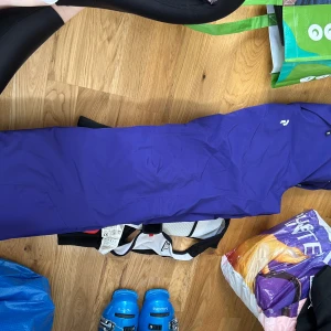 Lila täckbyxor från Peak Performance - Säljer ett par lila täckbyxor från Peak Performance i damstorlek XS. Byxorna har dragkedja och knappar framtill samt praktiska fickor. Perfekta för vinterns alla äventyr. (Sidor eller leka i snön) tillhörande hängslen saknas/medföljer ej.