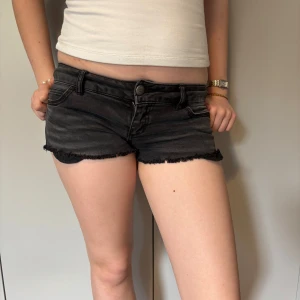 Svarta jeansshorts med fransig kant från ONLY - Säljer ett par svarta jeansshorts från ONLY med fransig kant nertill. Shortsen har klassisk femficksdesign, knapp- och dragkedjestängning samt låg midja. Perfekta för varma dagar och enkel att matcha med olika toppar.