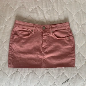 Rosa jeanskjol från vero moda  - Säljer en söt rosa jeanskjol. Kjolen har klassisk femficksdesign, bälteshällor och knapp- samt dragkedjestängning framtill. Perfekt för dig som gillar en enkel men trendig look.