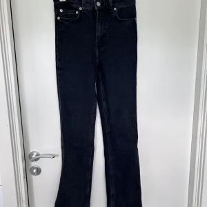 Svarta jeansbyxor från 157 - Säljer ett par svarta jeansbyxor från 157 i klassisk femficksmodell. Byxorna har raka ben och hög midja, med silverfärgade knappar och nitar. Perfekta för en stilren och enkel look.